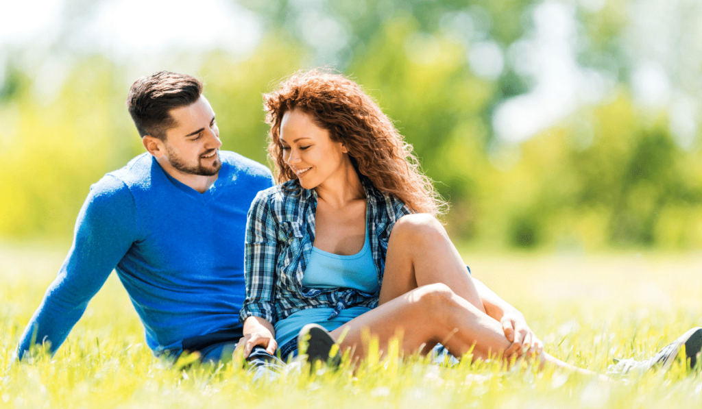 There's a man and a woman who are sitting together on the grass